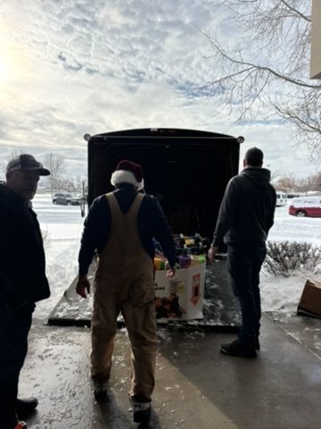 Volunteers loading boxes of toys into a truck in the snow