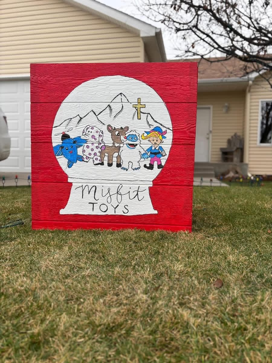 A hand-painted Misfit Toys snow globe sign in a front yard