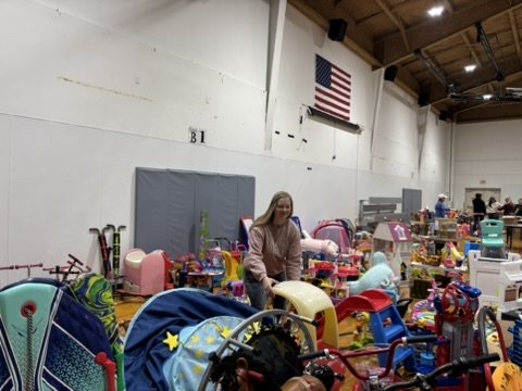A volunteer arranging toys on tables in the gym